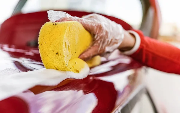 年轻女子洗车侧 用塑料手套手拿着黄色海绵进行特写 — 图库照片