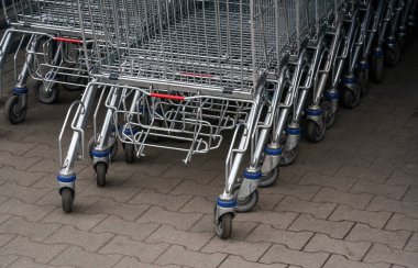 Alışveriş merkezinin önünde yığılmış metal alışveriş arabaları, alt kısımda ve tekerleklerde detaylar