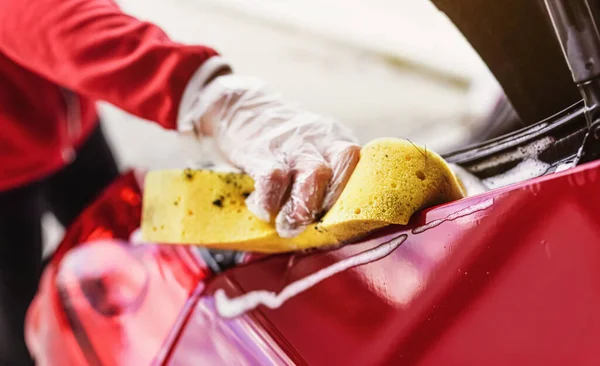 年轻女子手握黄色海绵 手握手套 清洁后部的汽车 进行特写 — 图库照片