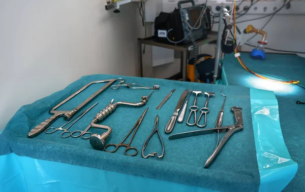 青い布の上に鋼の外科用ツールのセット モバイル医療軍のテントで使用される実際の楽器 ぼやけた操作テーブルの背景 — ストック写真