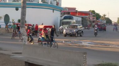 Toliara, Madagaskar - 30 Nisan 2019: Ana yoldaki tipik akşam manzarası, insanlar yürüyor, bisiklet rikşovu ve motosiklet geçiyor, yan taraftaki dükkanlar