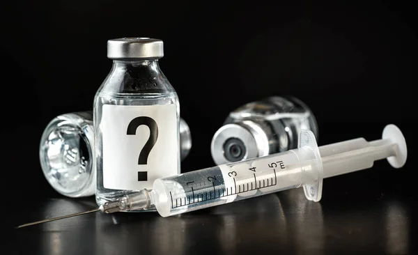 皮下注射针头附近的疫苗瓶 标签上的问号 黑色背景 实验治疗概念的未知副作用 — 图库照片