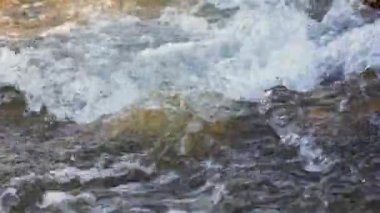 Güneşli bir günde kayaların üzerinden akan hızlı kaynak nehri, beyaz su dalgaları oluşturur, yakın plan detayları- soyut doğa arkaplanı