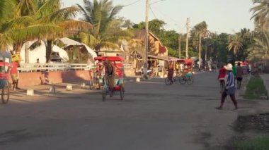 Toliara, Madagaskar - 30 Nisan 2019: Ana yoldaki tipik akşam manzarası, insanlar yürüyor, bisikletli fayton geçiyor, yan taraftaki dükkanlar