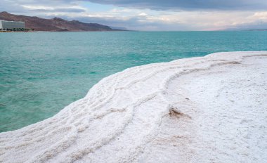 Beyaz tuz kristalleri, berrak yeşil sakin su yakınında, Ein Bokek plajında tipik manzara, İsrail