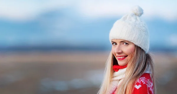 白い冬の帽子と赤いジャンパーの若い女性の肖像 彼女の笑顔に近い顔 左側のテキストのためのスペース — ストック写真