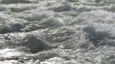 Yakından bakınca, güneşli bir günde nehirde akan su beyaz dalgalar oluşturuyor.