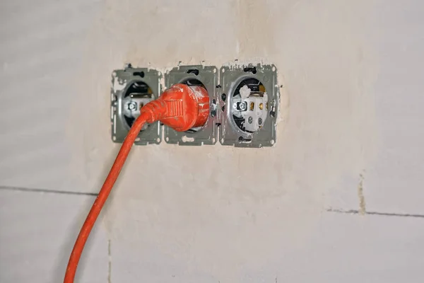 Orange Power Lead Connected Provisional Electric Socket Bare Wall House — стоковое фото