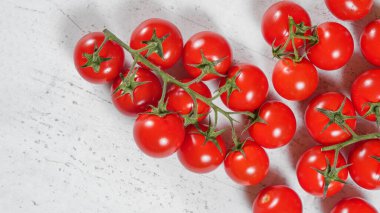 Canlı küçük kırmızı domatesler, yeşil sarmaşıklı beyaz kayalar, tahta gibi yukarıdan görünüyor.