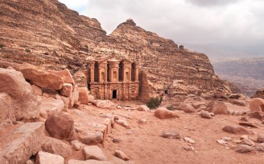 Ad Deir - Manastır - Petra Ürdün 'ün kayalık duvarına oyulmuş harabeler, mavi gökyüzü arka planlı dağlık arazi