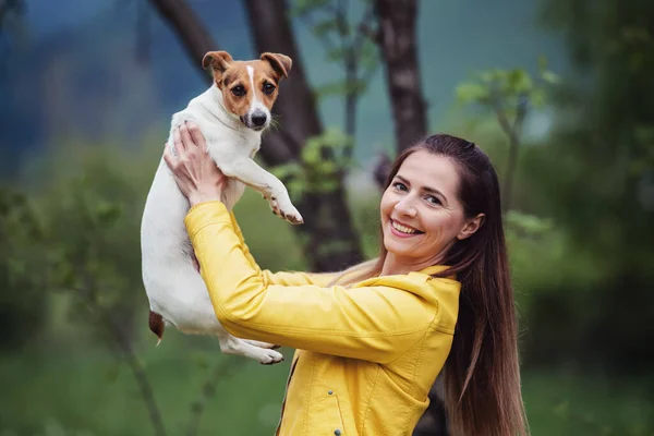 Молодая Женщина Жёлтой Куртке Держит Руках Свою Собаку Терьера Джека — стоковое фото