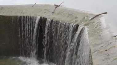 Su, göl kıyısındaki beton kanaldan dökülüyor.