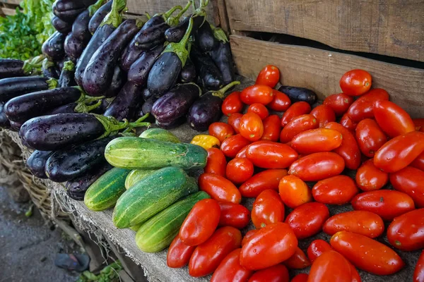 stock image Eggplants or aubergines, cucumbers and oval tomatoes on display at street market in Africa, closeup detail