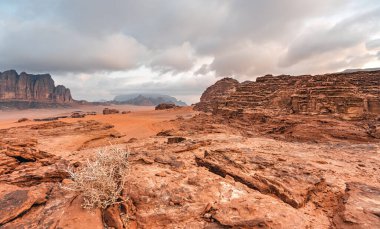 Wadi Rum Çölü 'ndeki Rocky manzarası Mars gezegenini anımsatıyor. Bulutlu bir sabahta, uzaktan görülebilen küçük kamp çadırları.