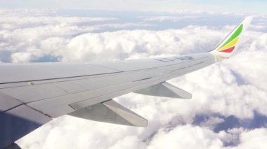 Addis Ababa, Etiyopya - 07 Mayıs 2019: Etiyopya havayollarının yolcu penceresinden görülen Boeing 737 ticari uçağı, mavi gökyüzünde uçağın altında görünen bulutlar, kanat ucunda kırmızı sarı logo
