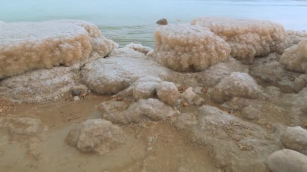 死海沿岸の結晶塩で覆われた砂 近くのターコイズブルーの水 イスラエルのEin Bokekビーチの典型的な風景 — ストック動画