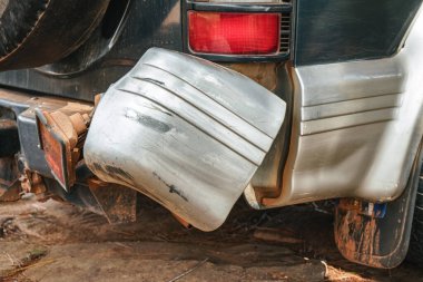 Kırık stop lambası, kırmızı tozdan kirlenmiş, 4x4 off road aracı, plastik tampon çizilmiş ve eğilmiş.
