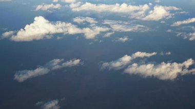 Uçak penceresinden bak - güneşin aydınlattığı kabarık bulutların üzerinde uçuyor