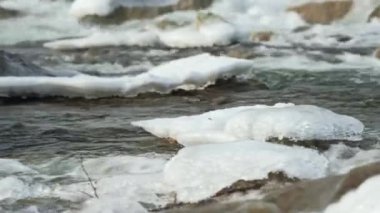 Kar ve buzla kaplı taşların yanında akan kış nehri.