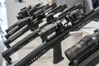 Silah fuarında sergilenen metal çubuğa monte edilmiş siyah dürbün optikleri, ayarlama düğmelerine yakın çekim detayları