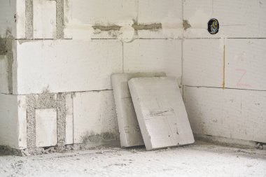 AAC 'den inşa edilen yeni boş duvarlar - otomatik klavyeli hücre betonu, elektrik prizleri için kablolu kutu görünür, yerde köpük polistiren yalıtım tahtaları.