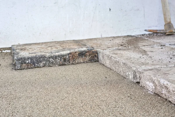 Large old concrete tile blocks on layer of sand - pavement construction, closeup detail.