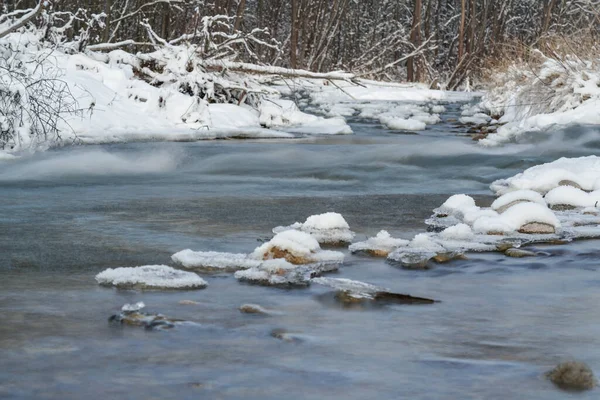 Winter river surface with snow crystals and ice floating on water - long exposure photo, surface is silky smooth