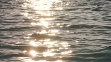 Öğleden sonra ya da akşam güneşi denizi sakinleştirmek için parlar, ışık küçük dalgaları yansıtır, yavaş çekim yakın çekim detayı