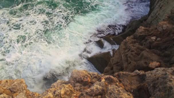 海は岩だらけの海岸に衝突し 緑色の水が飛び散り 白い泡を作り出し 上からの眺め スローモーションビデオ — ストック動画