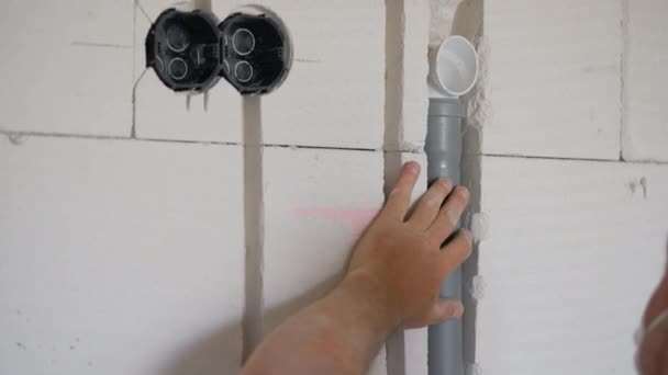 建筑工人将电缆用塑料管安装在白色混凝土砖墙的追赶槽中 详情仅限手操作 — 图库视频影像