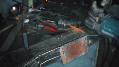 Man working with rotary angle grinder at workshop, closeup detail, orange sparks flying around