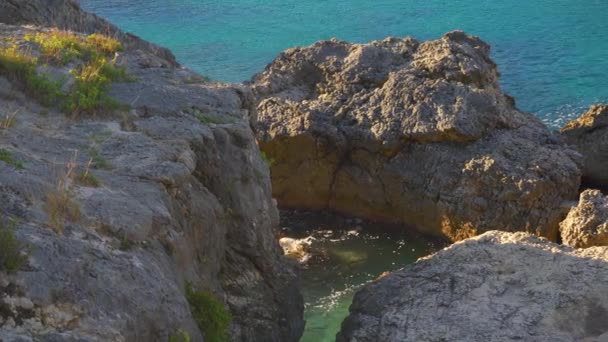 大きな岩が付いている海岸の穏やかな緑の海 太陽は小さな波に輝き カメラは側面に ギリシャのリピアデスで多くのベイの1つで典型的な景色をパンします — ストック動画