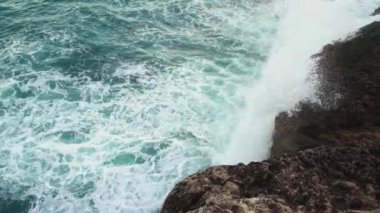 Kayalık kıyıya vuran deniz, sıçrayan yeşil su, yukarıdan görünen beyaz köpük, yavaş çekim videosu
