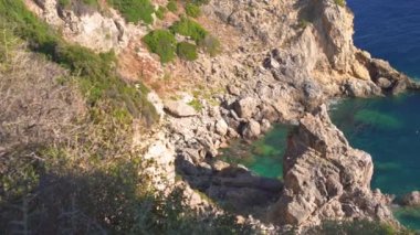 Paleokastritsa, Korfu Yunanistan 'daki yüksek kayalıklardan aşağıya bakan, aşağıdaki berrak yeşil deniz suyu