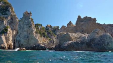 Suyun üzerinde görünen yüksek kayalık kayalıklar - Paleokastritsa yakınlarında tipik deniz manzarası, Corfu Yunanistan, bir tekneden manzara, manastır dağın arka planında görülebilir