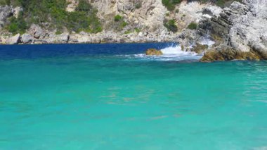Güneş turkuaz renkli denizlerde parlıyor, küçük dalgalar, arka planda kayalık uçurumlar - tipik Rovinia sahili, Liapades Corfu