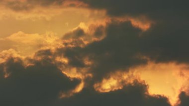 Güneş bulutların arasından batıyor, bazı kuşlar ön planda uçuyor.