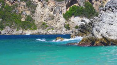 Güneş turkuaz renkli denizlerde parlıyor, küçük dalgalar, arka planda kayalık uçurumlar - tipik Rovinia sahili, Liapades Corfu