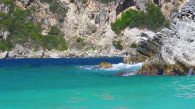 Güneş turkuaz renkli denizlerde parlıyor, küçük dalgalar, arka planda kayalık uçurumlar - tipik Rovinia sahili, Liapades Corfu