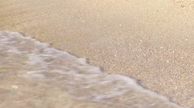 Kumsal, güneşle aydınlanıyor, deniz suyu kıyıya vuruyor, yakın plan ayrıntıları - tropikal tatil arka planının sığ derinliği