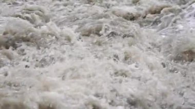 Rapid dirty river waves, drops of water flying in air, closeup slow motion video
