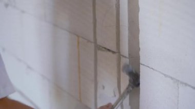 Construction worker expanding electric cable chase grooves with wall chisel, detail on hands holding the hitting hammer