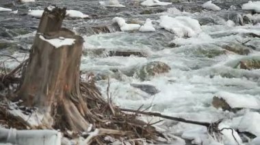 Kış nehri karla kaplı ve buzla kaplı taşlarla dolu, yakın plan detaylar.