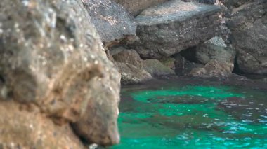 Kayalık sahil kıyısındaki oldukça sakin yeşil deniz, güneş küçük dalgalara parlıyor, Yunanistan 'ın Liapades kentindeki pek çok koydan birinde tipik manzara