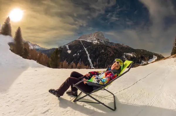 意大利塞拉隆达Dolomites市滑雪后坐在扶手椅上休息的年轻女子 图库照片