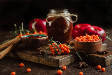 Kavanozda elma ve deniz dikenli karides reçeli, taze böğürtlen ve meyve, tarçın baharatları ve kahverengi ahşap arka planda anason.