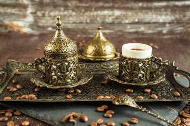 Geleneksel Türk kahvesi eski bardakta, metal serviste, anason, kahverengi arka planda kavrulmuş fasulye.