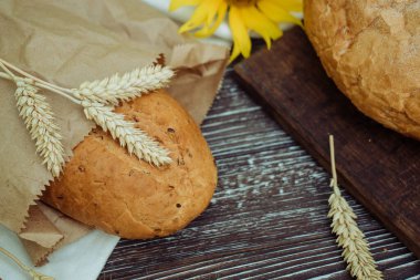 freshly bread with flax seeds, sunflower, ears of wheat on a brown wooden background, home baking 1