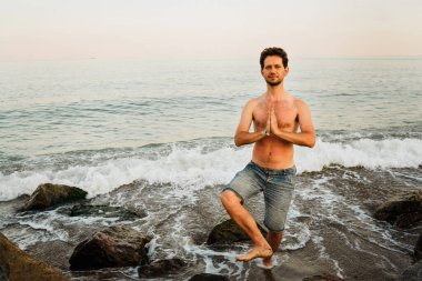 happy man practices indian classical yoga meditation by the sea. Place for text