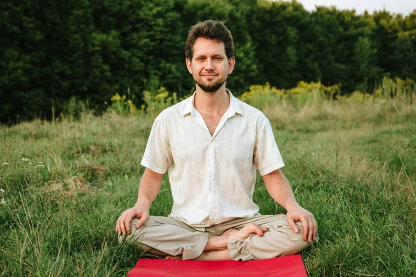 Doğada Yoga Yapan Genç Bir Adam Gülümseyerek Lotus Pozisyonunda Oturuyor — Stok fotoğraf